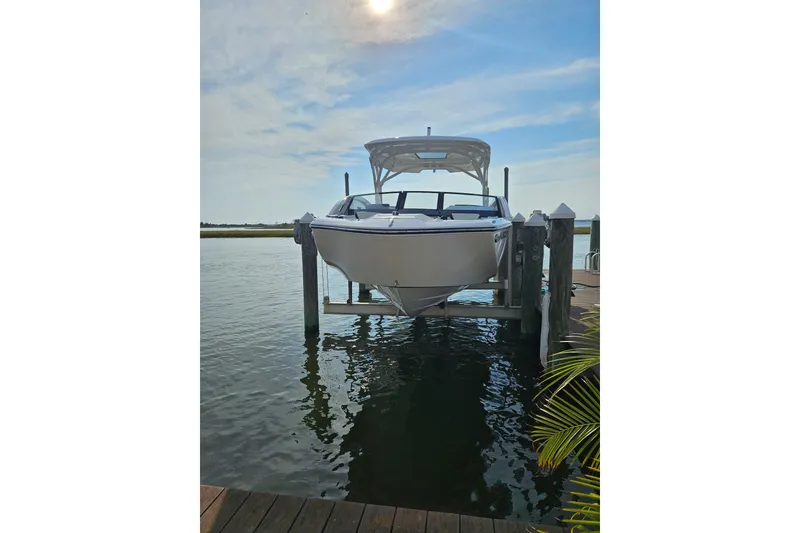 Slide: The Image of 2024 Yamaha Boats 275SD on lift, docked by serene waters under a blue sky. - 9