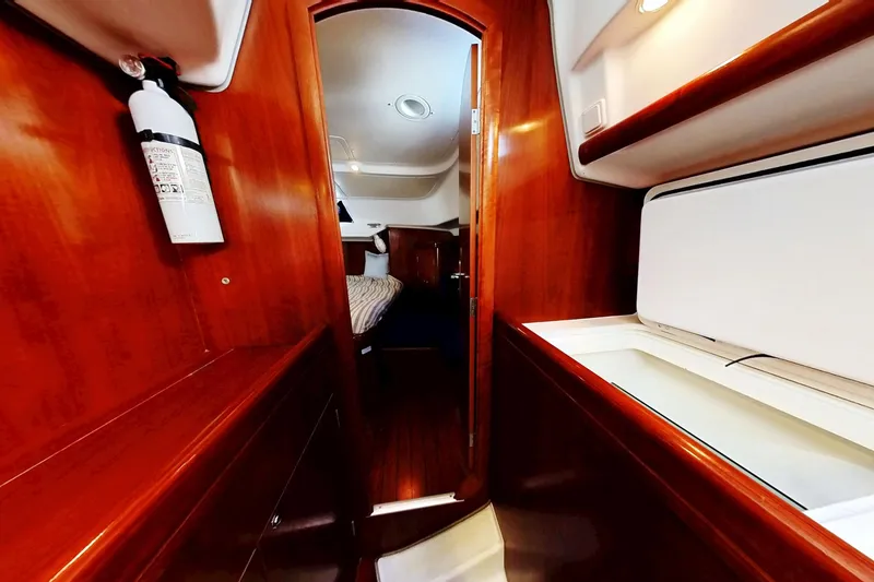 Slide: The Image of Interior of 2003 Beneteau Oceanis 42CC yacht, featuring wood paneling and cozy cabin space. - 15