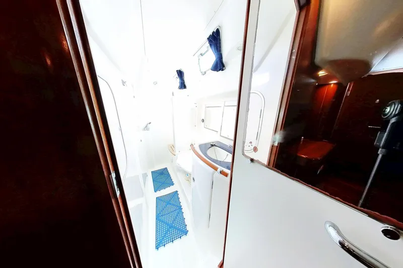 Slide: The Image of Interior of 2003 Beneteau Oceanis 42CC yacht, featuring a bright bathroom with blue mats. - 21