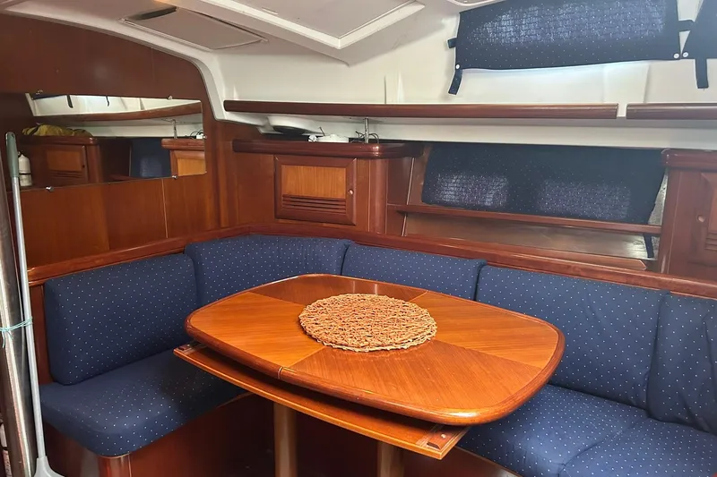Slide: The Image of Interior of 2003 Beneteau Oceanis 42CC yacht with wooden table and blue seating. - 31