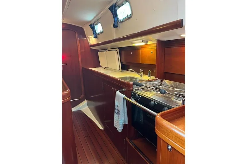Slide: The Image of Interior of 2003 Beneteau Oceanis 42CC yacht, featuring a compact kitchen with wood finish. - 34