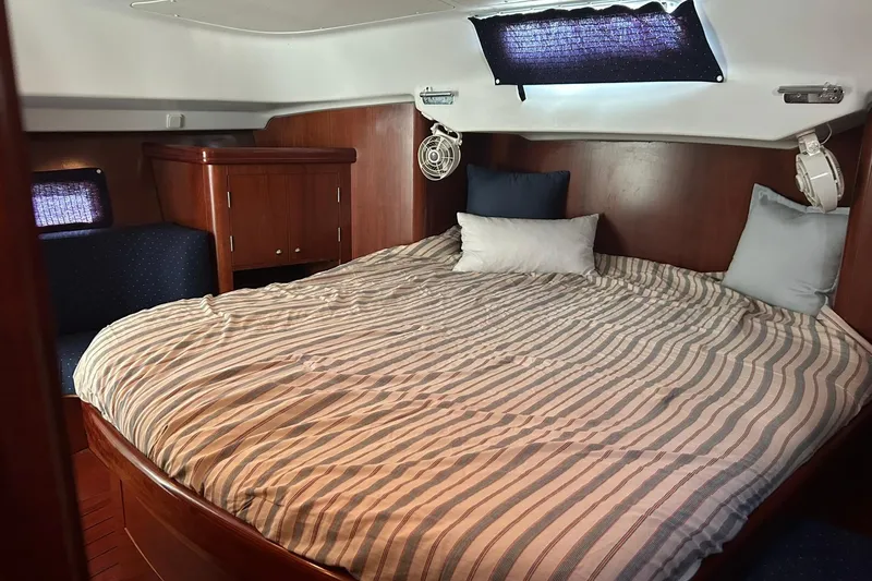 Slide: The Image of Cozy cabin interior of 2003 Beneteau Oceanis 42CC with striped bedding and wooden finish. - 46