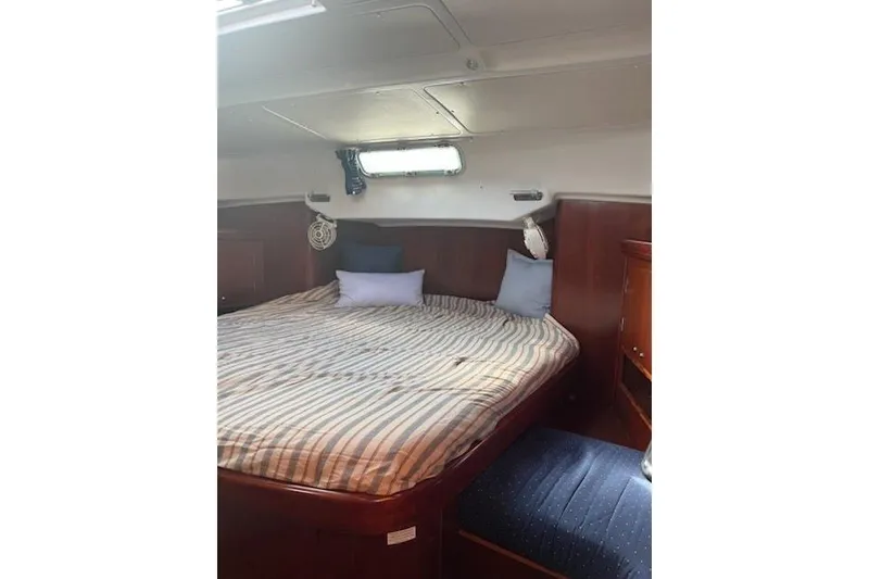 Slide: The Image of Cozy cabin interior of 2003 Beneteau Oceanis 42CC with striped bedding and wooden furnishings. - 47
