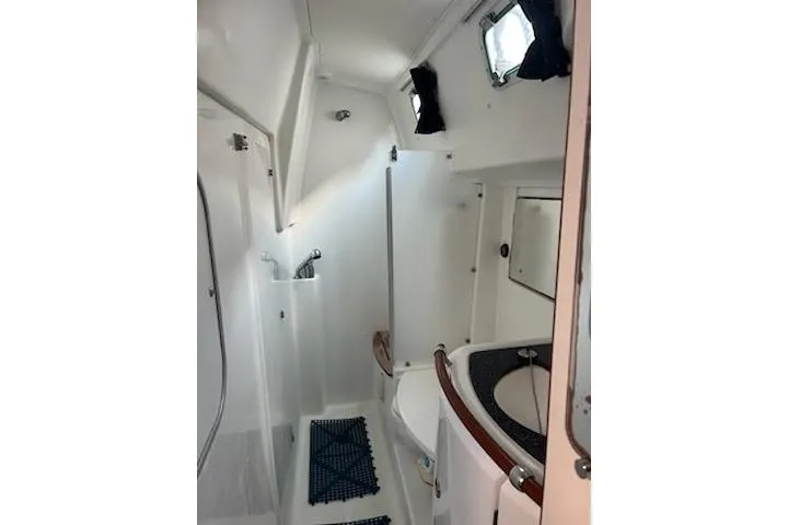 Slide: The Image of 2003 Beneteau Oceanis 42CC yacht bathroom with shower, sink, and porthole window. - 53