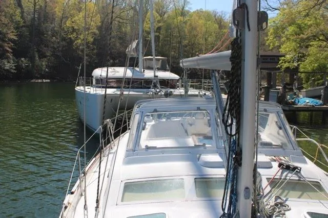 Slide: The Image of 2003 Beneteau Oceanis 42CC sailboat docked in a serene, wooded marina setting. - 71