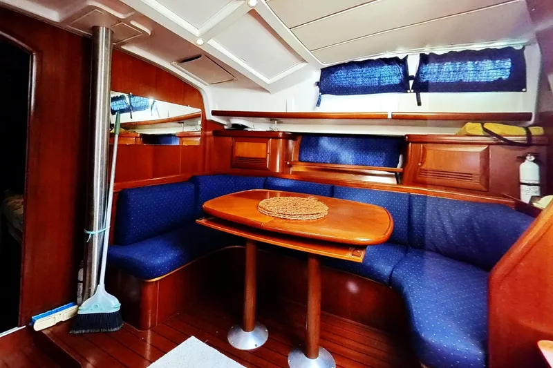 Slide: The Image of Interior of 2003 Beneteau Oceanis 42CC yacht with wooden dining area and blue seating. - 9