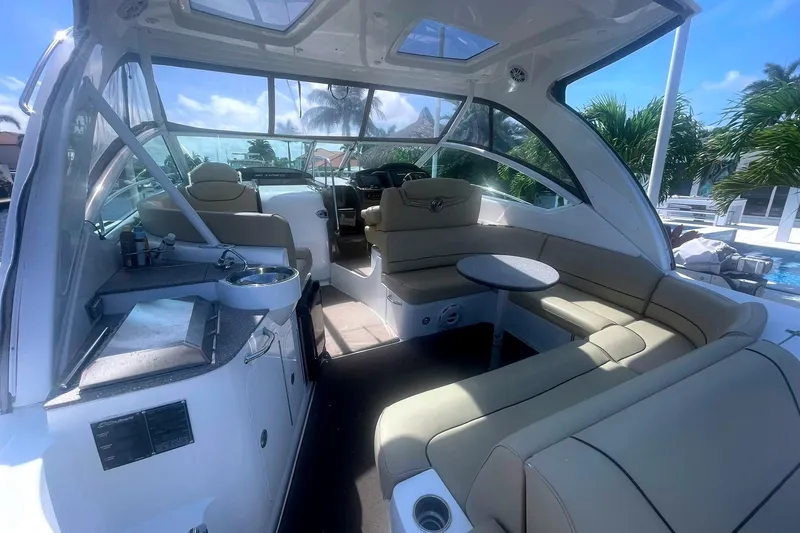 Slide: The Image of 2014 Cruisers Yachts 380 Express interior with seating, table, and kitchenette under a sunny sky. - 8