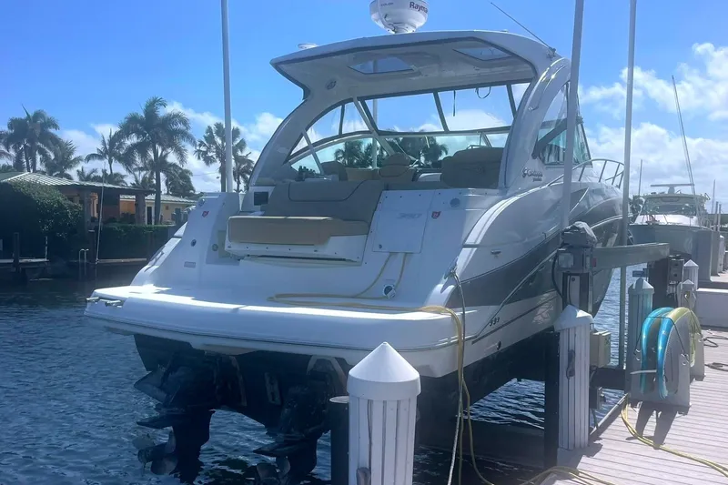 Slide: The Image of 2014 Cruisers Yachts 380 Express on lift at marina, surrounded by palm trees. - 2