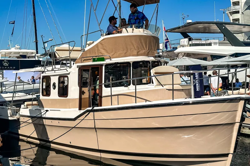 The Image of 2026 Ranger Tugs R-31 CB boat docked at marina, featuring upper deck and beige exterior. - 0