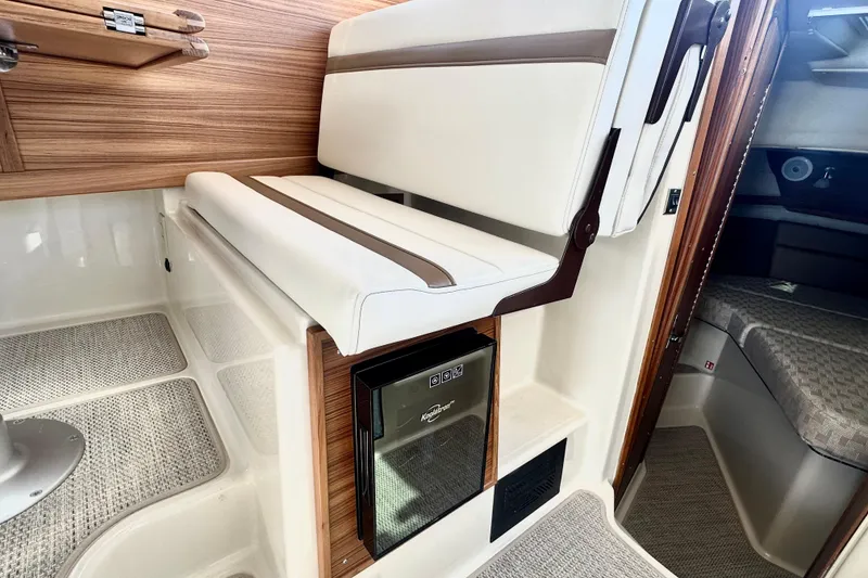 Slide: The Image of 2026 Ranger Tugs R-31 CB interior with cushioned seating and compact refrigerator. - 11