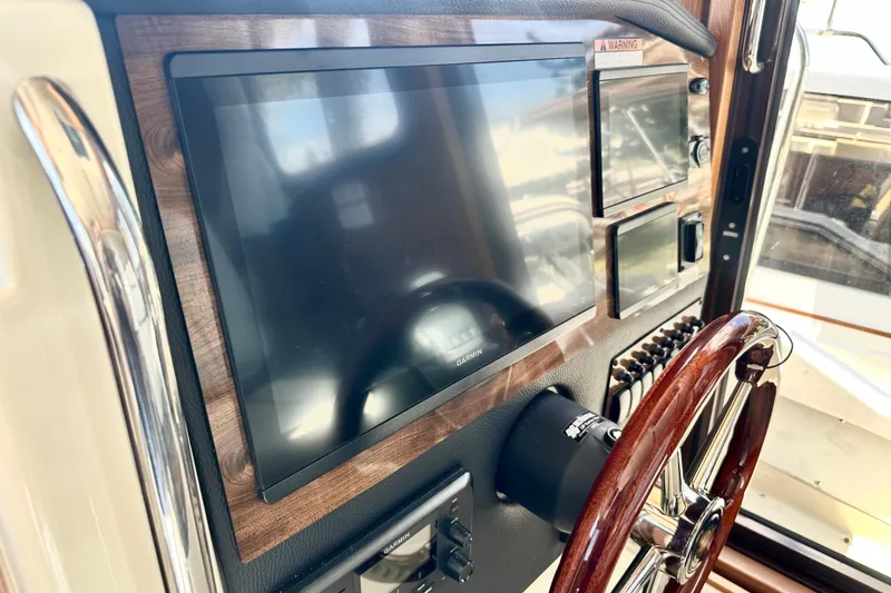 Slide: The Image of 2026 Ranger Tugs R-31 CB helm with modern navigation displays and wooden steering wheel. - 21