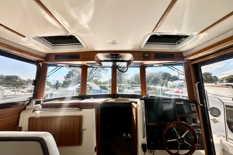Slide: The Image of 2026 Ranger Tugs R-31 CB boat interior with helm, windows, and wooden accents. - 24