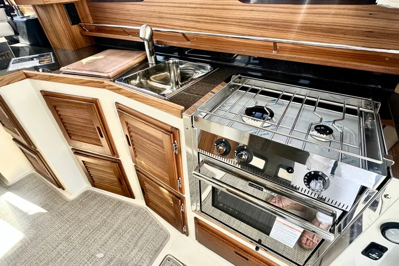 Slide: The Image of 2026 Ranger Tugs R-31 CB kitchen with stove, sink, and wooden cabinets. - 4