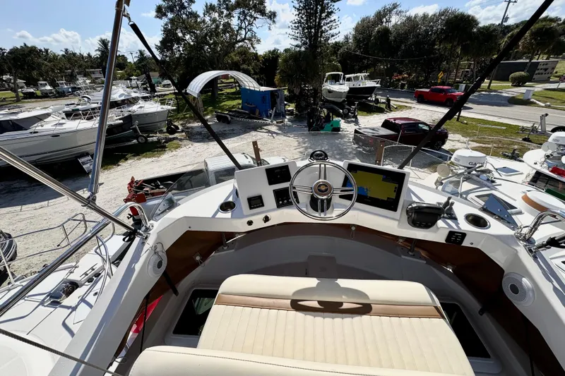 Slide: The Image of 2026 Ranger Tugs R-31 CB helm with navigation screens and steering wheel, docked in a marina. - 46