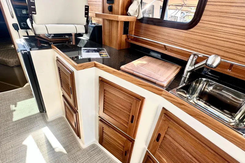 Slide: The Image of 2026 Ranger Tugs R-31 CB interior kitchen with wood cabinetry and stainless steel sink. - 6