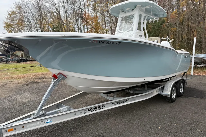 Slide: The Image of 2022 Tidewater 232 SS boat with beige seating and rod holders, parked outdoors. - 5