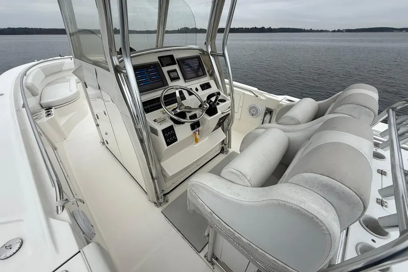 Slide: The Image of 2013 Edgewater 318CC boat interior with dual seats and control panel on calm water. - 17