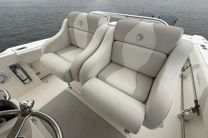 Slide: The Image of 2013 Edgewater 318CC boat with plush dual seats, steering wheel, and ocean backdrop. - 18