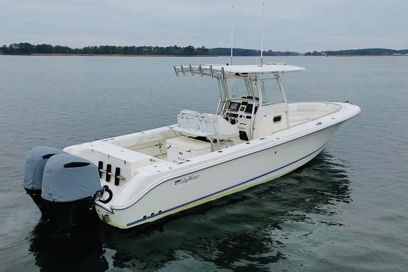 Slide: The Image of 2013 Edgewater 318CC boat on calm water, featuring twin engines and a sleek design. - 7