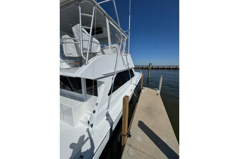 Slide: The Image of 2000 Viking 50 Convertible yacht docked at a marina under clear blue skies. - 22
