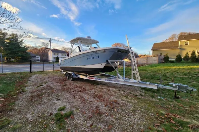 Slide: The Image of 2024 World Cat 260 DC-X boat on trailer in residential yard, under blue sky. - 5