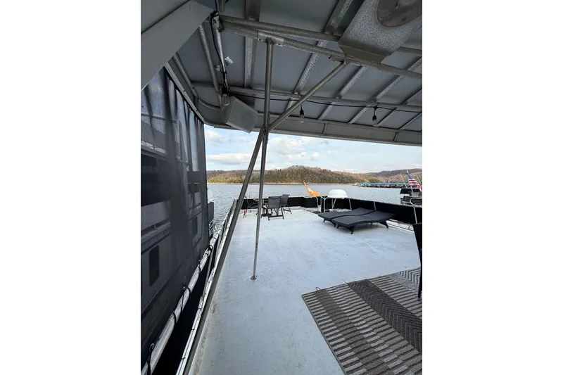 Slide: The Image of Stardust Cruisers 2000 houseboat deck with lake view, featuring lounge chairs and canopy. - 17