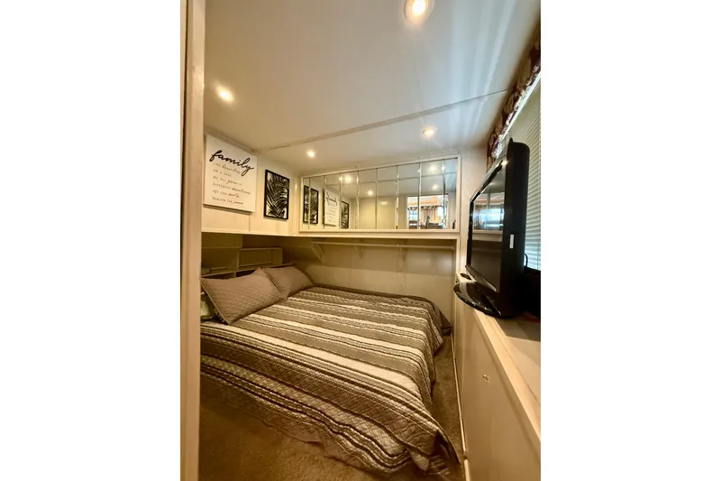 Slide: The Image of Cozy bedroom in 2000 Stardust Cruisers houseboat with striped bedding and wall art. - 9