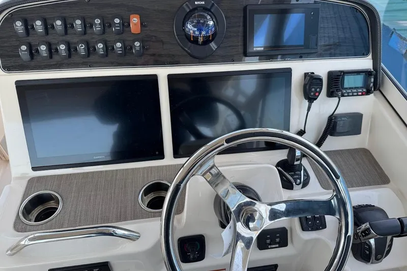Slide: The Image of Control panel of 2022 Grady-White Freedom 335 boat with steering wheel and navigation screens. - 13