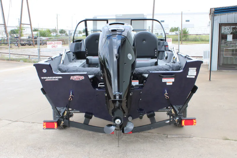 Slide: The Image of 2026 Tracker Pro Guide V-16 WT boat, rear view with motor, parked outdoors. - 12