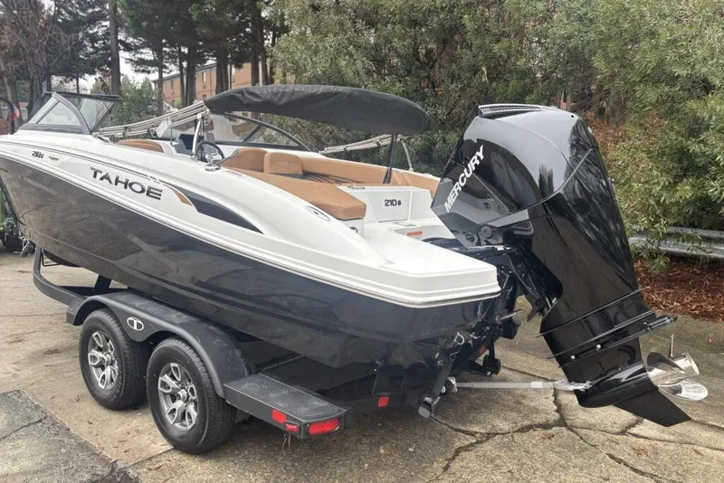 Slide: The Image of 2026 Tahoe 210 S boat on trailer with Mercury outboard motor, parked outdoors. - 112