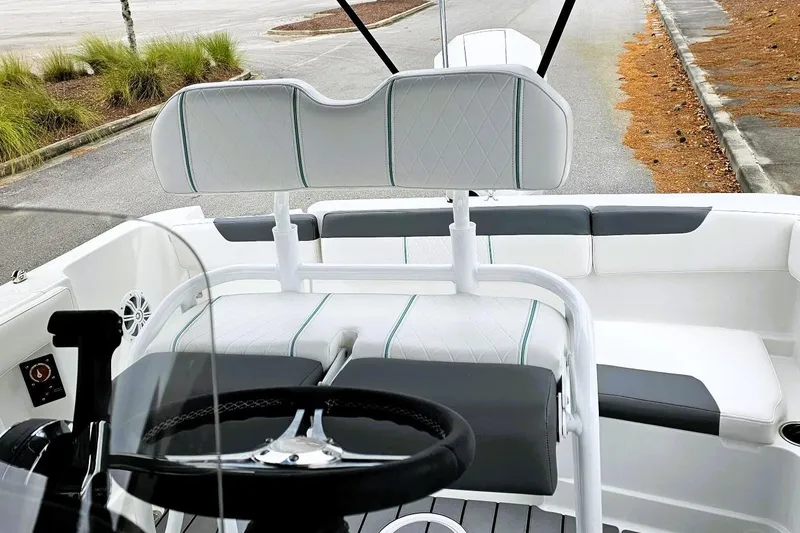 Slide: The Image of 2026 Tahoe 2150 CC boat with outboard motor and canopy, parked on a road. - 10