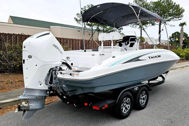 Slide: The Image of 2026 Tahoe 2150 CC boat with Mercury engine on a trailer, parked outdoors. - 2