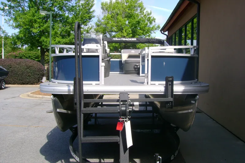 Slide: The Image of 2026 Sun Tracker Bass Buggy 16 XL Select pontoon boat on trailer, parked outdoors. - 3