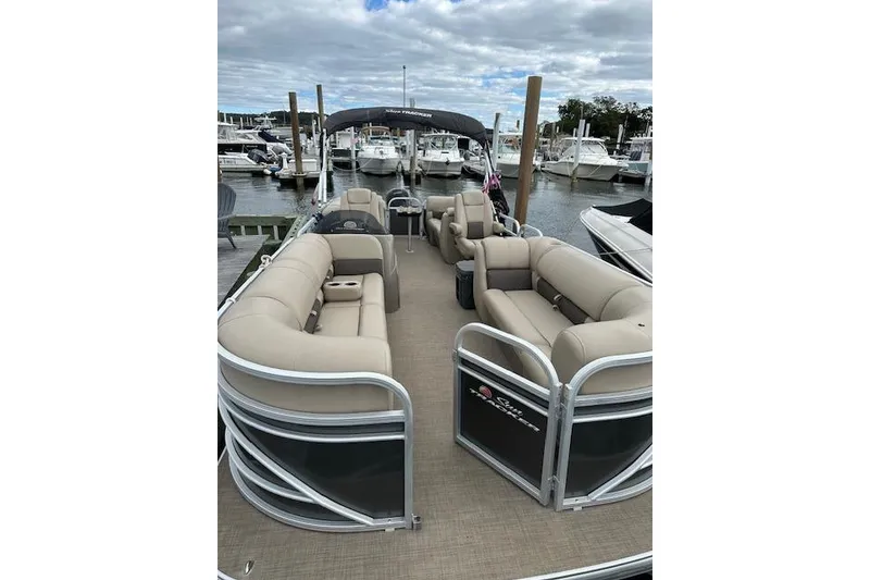 The Image of 2021 SUNTRACKER Tracker Marine pontoon boat with beige seating at a marina. - 0