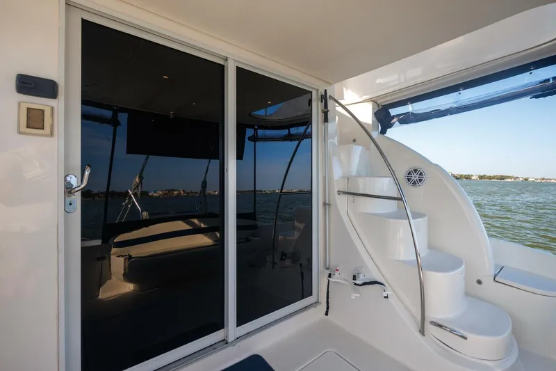 Slide: The Image of 2010 Meridian 391 Sedan yacht with sleek glass doors and curved staircase by the water. - 22
