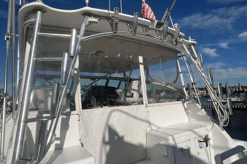 Slide: The Image of 2004 Henriques 35 Express boat with fishing rod holders and clear cockpit enclosure. - 21