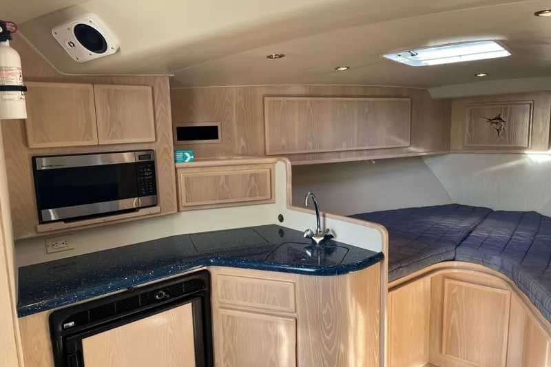 Slide: The Image of 2004 Henriques 35 Express cabin interior with kitchenette and bed, featuring wood cabinetry and modern amenities. - 49