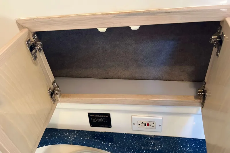 Slide: The Image of Open cabinet on 2004 Henriques 35 Express boat with electrical outlet and tank level monitor. - 75