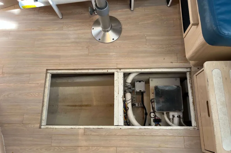 Slide: The Image of 2004 Henriques 35 Express boat interior showing open floor panel with visible wiring and pipes. - 79