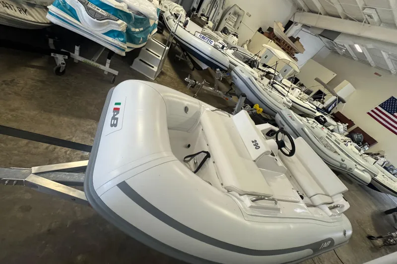 Slide: The Image of 2024 AB Inflatables ABJET 290 boat displayed in a showroom with other boats. - 1
