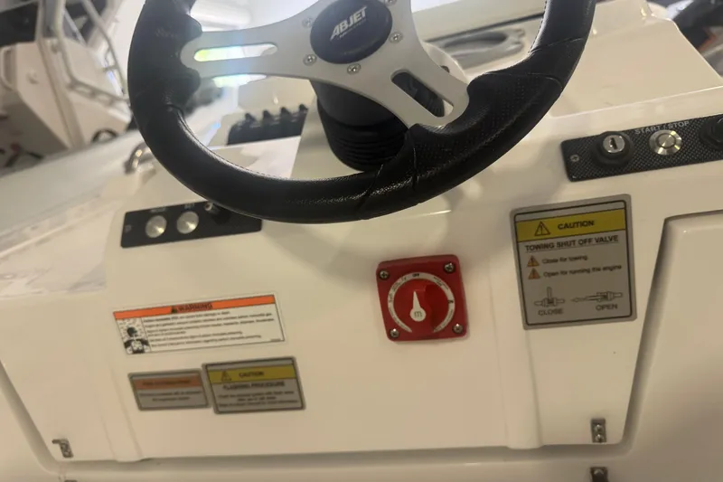 Slide: The Image of 2024 AB Inflatables ABJET 290 steering console with controls and safety warnings. - 5