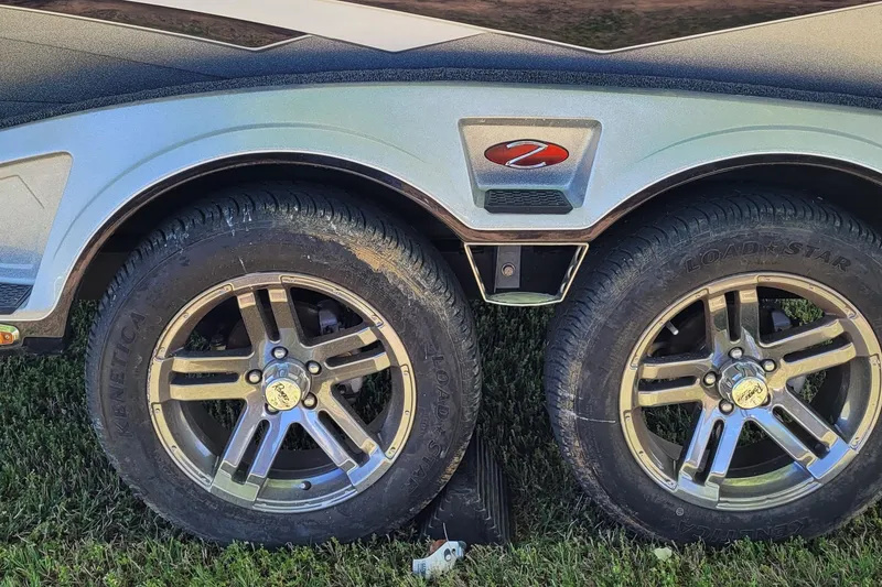 Slide: The Image of 2020 Ranger Z521L trailer wheels on grass, featuring Load Star tires and alloy rims. - 6