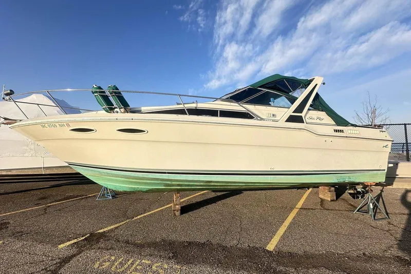 Slide: The Image of 1987 Sea Ray 300 Sundancer boat on dry dock under clear sky. - 1
