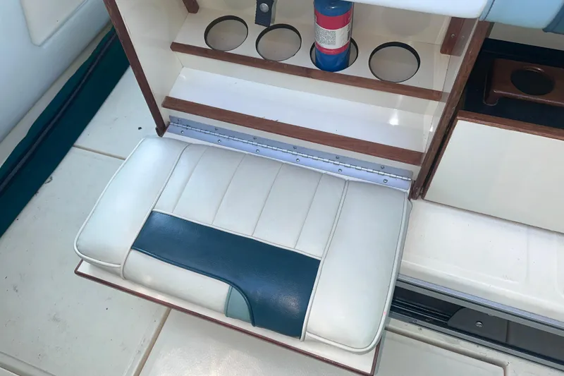 Slide: The Image of 1987 Sea Ray 300 Sundancer interior with white and blue cushioned seat and cup holders. - 12