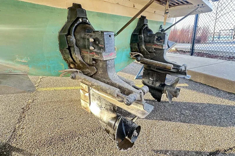 Slide: The Image of 1987 Sea Ray 300 Sundancer boat outdrives on pavement, showcasing dual propellers. - 2