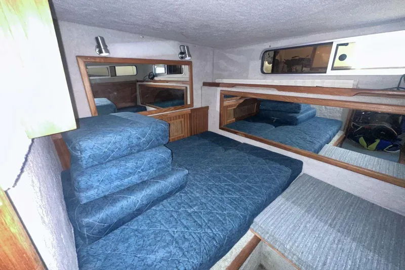 Slide: The Image of Interior cabin of 1987 Sea Ray 300 Sundancer with blue bedding and wood accents. - 29