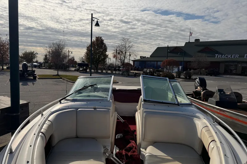 Slide: The Image of 1995 Sea Ray 200 Bow Rider boat parked near a marina under a cloudy sky. - 2