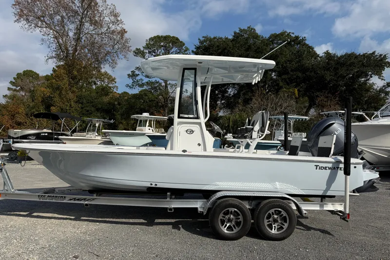 Slide: The Image of 2026 Tidewater 2110 Bay Max boat on trailer, parked outdoors under a cloudy sky. - 2