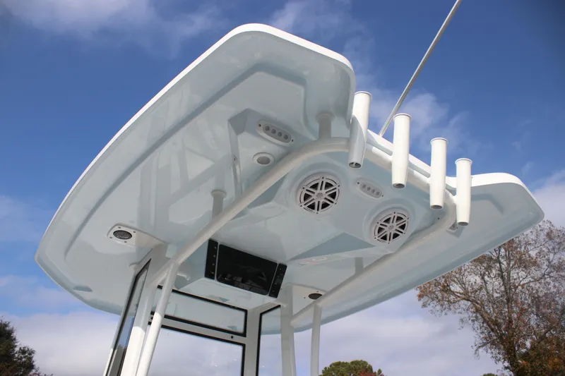 Slide: The Image of Tidewater 2110 Bay Max 2026 boat T-top with rod holders and speakers against blue sky. - 26