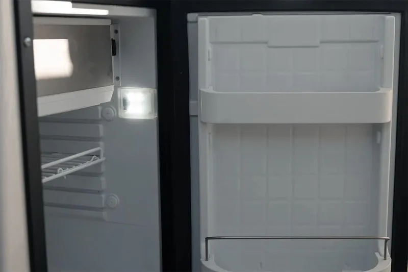 Slide: The Image of Manufacturer Provided Image: Open refrigerator inside 2025 Bayliner Trophy T23 Explorer boat, showing shelves and door storage. - 6